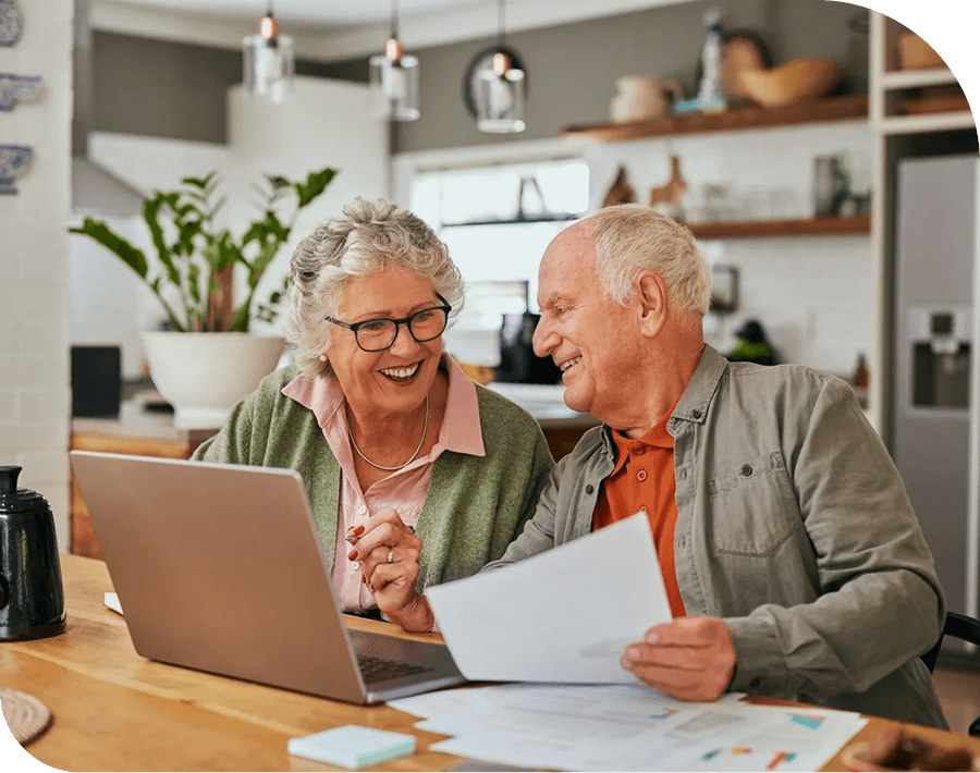 Elderly couple happily using a laptop together.